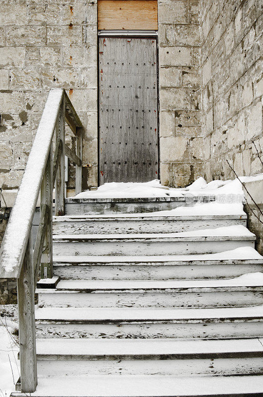 查看木制的雪覆盖的台阶，以封闭的门