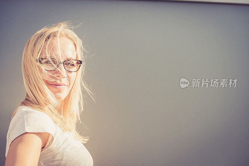 独立的年轻金发女人戴眼镜肖像户外