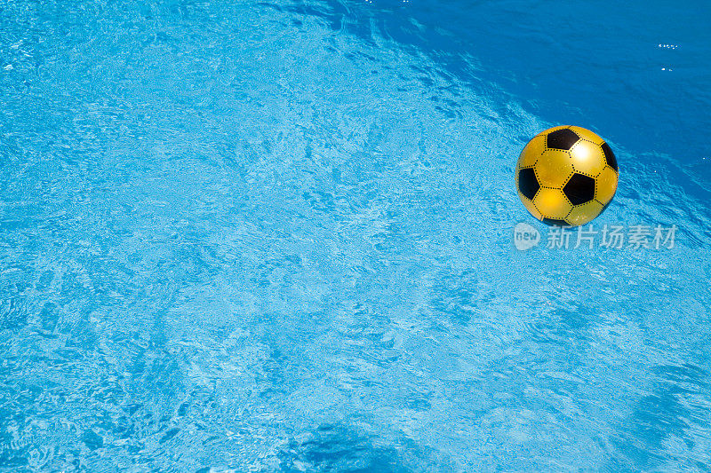 足球足球漂浮在美丽的阳光蓝色游泳池