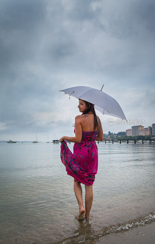 下雨天拿着伞站在海里的女人