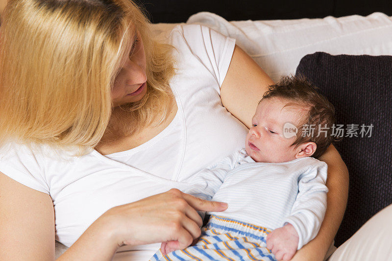 年轻的母亲和新生儿躺在她的胸前