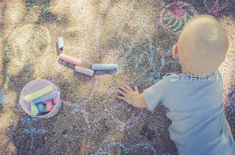 金发小孩在地板上玩彩色粉笔