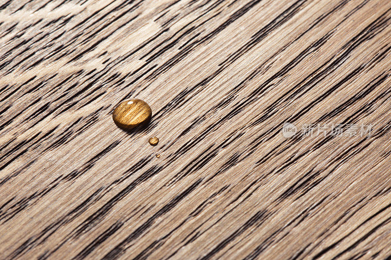 两滴水滴在木头表面，特写