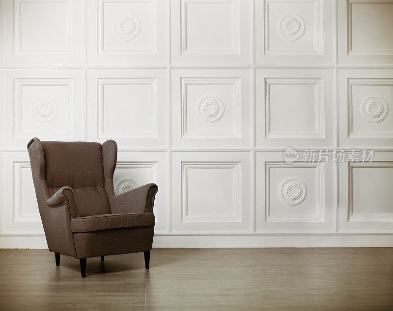 一张经典的扶手椅靠在白色的墙壁和地板上