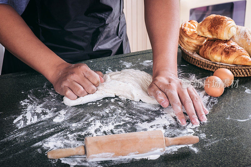 生面团为面包用配料以黑色为背景，揉面时男性用手撒上面粉