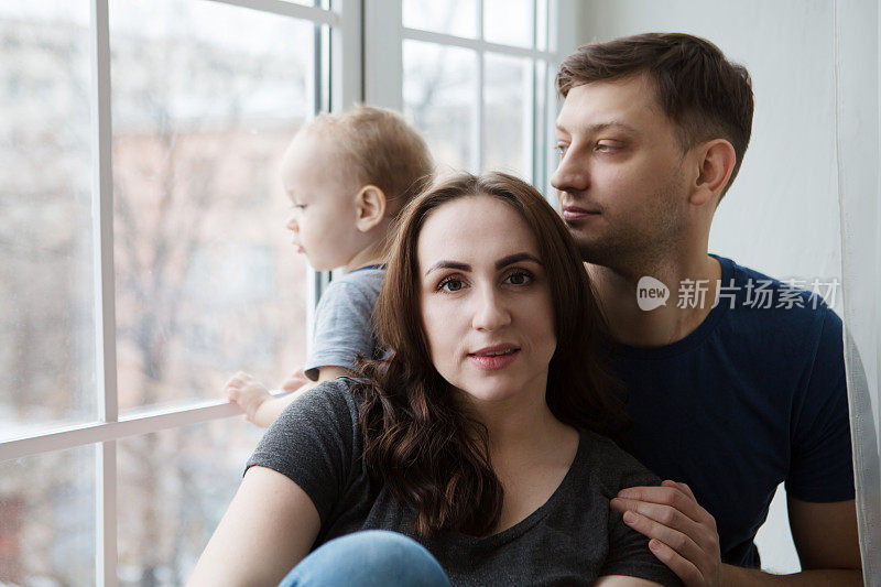 家庭母亲，父亲和孩子儿子看着窗外在一个雨天的秋天