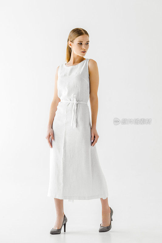 迷人的女人在亚麻白色连衣裙望着远离孤立的灰色背景