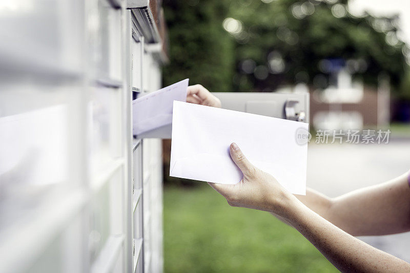 一个女人伸手到邮筒里取信
