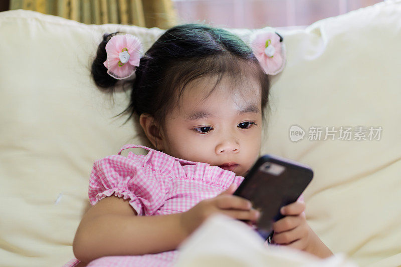 亚洲女婴在床上看智能手机