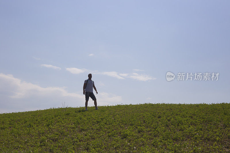 成年徒步旅行者在乡间的自然环境下，越过山的地平线