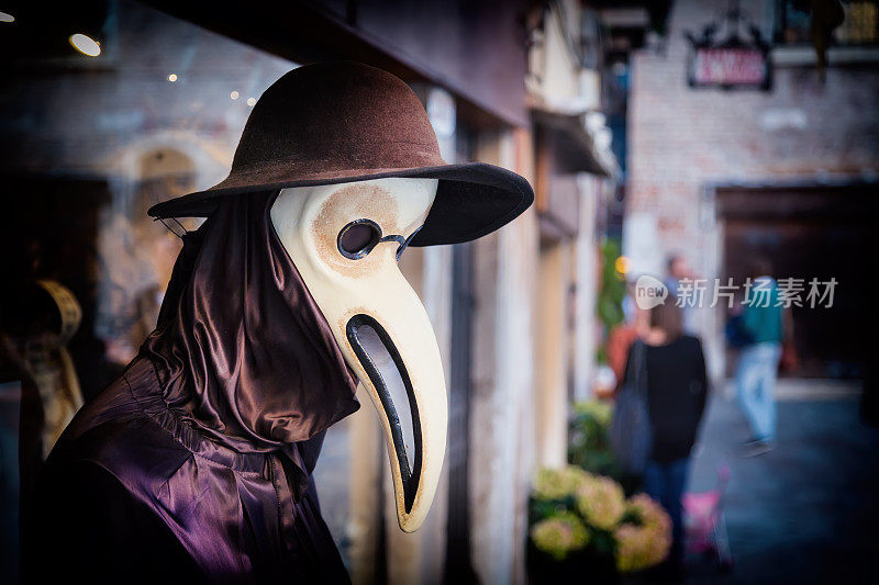 传统的威尼斯人体模型在瘟疫医生服装，面具和帽子附近的商店橱窗在威尼斯的街道，意大利。健美的形象。