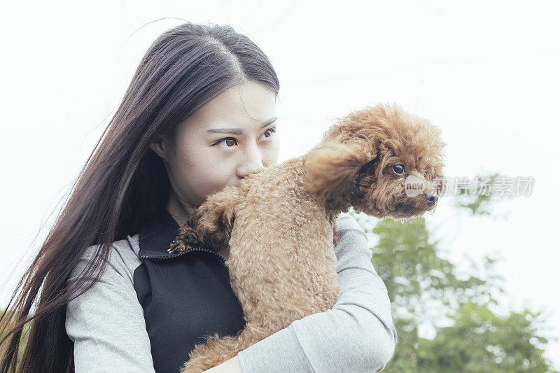 美丽的女人拥抱小狗泰迪对天空的特写