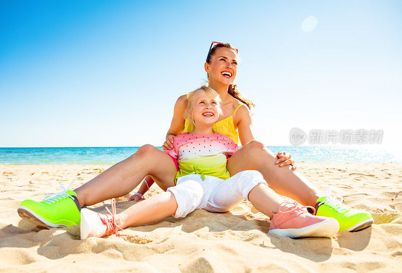 快乐时尚的母亲和孩子在海滩上望向远方