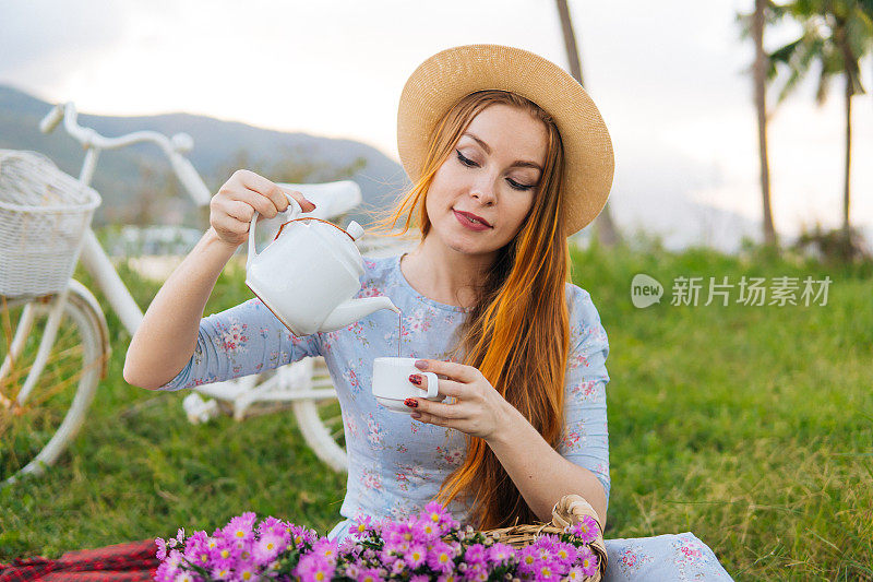 拿着茶壶和花的女人，享受野餐