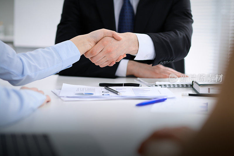 不知名的商务人士握手结束会议的特写。握手、协议或成功概念在人们的交际中