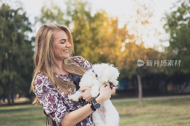 金发女人抱着一只可爱的马耳他狗