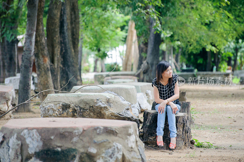 坐在树下长凳上的亚洲妇女