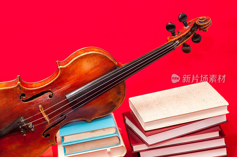 一堆书和一把旧小提琴放在不同的位置