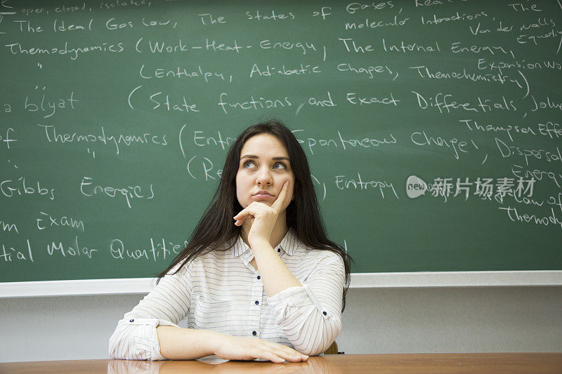 在黑板前深思熟虑的女学生