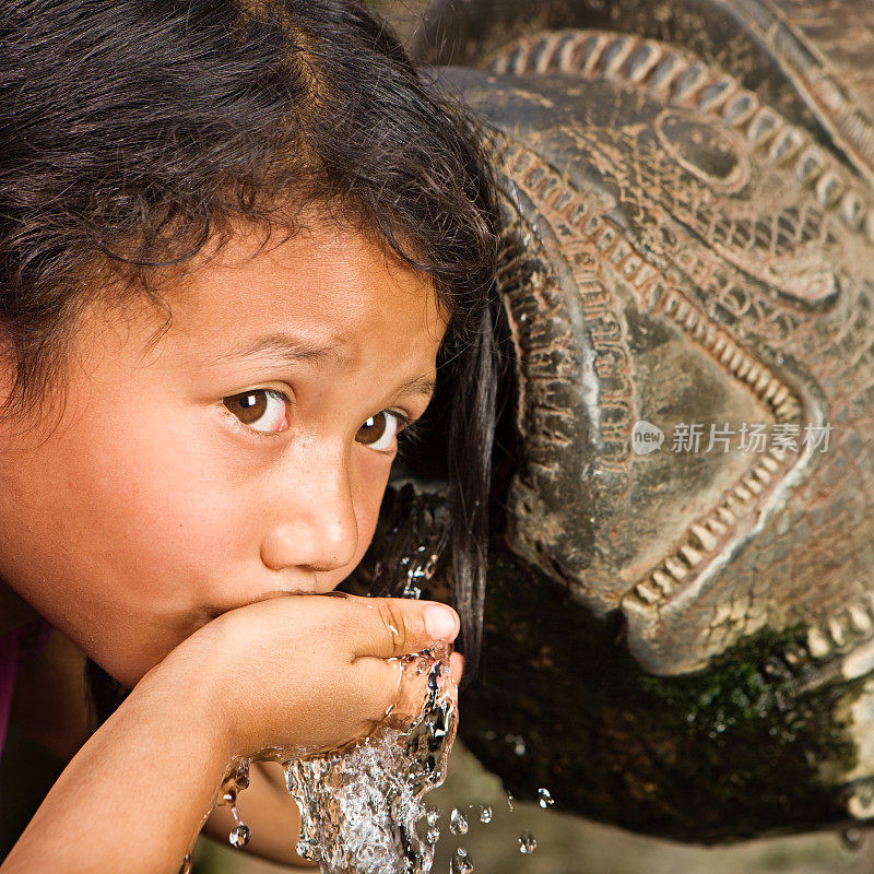 年轻的尼泊尔女孩在杜巴广场的城市喷泉中饮水