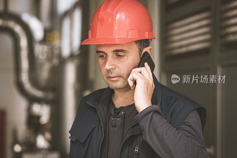 在工厂里使用手机的男性技术员