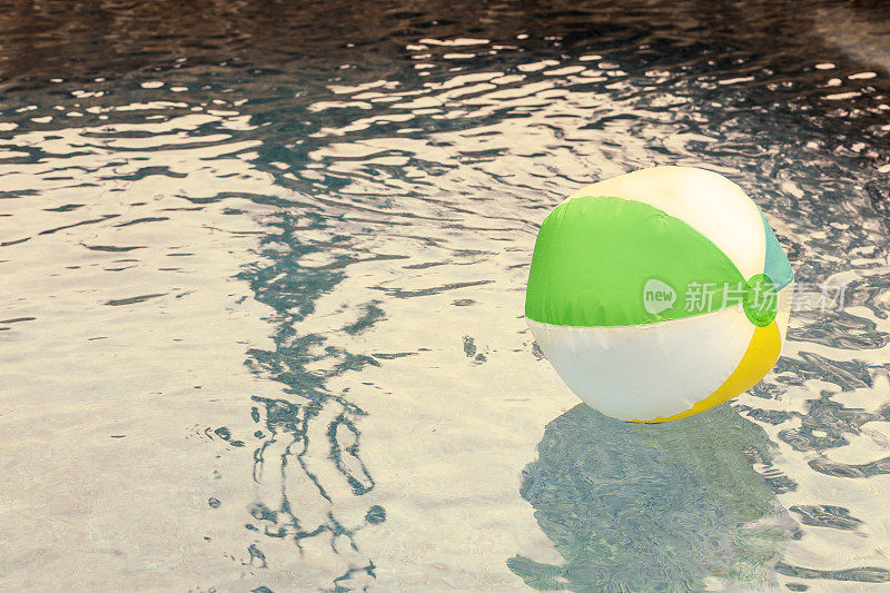 在清爽的游泳池水中漂浮的沙滩球。