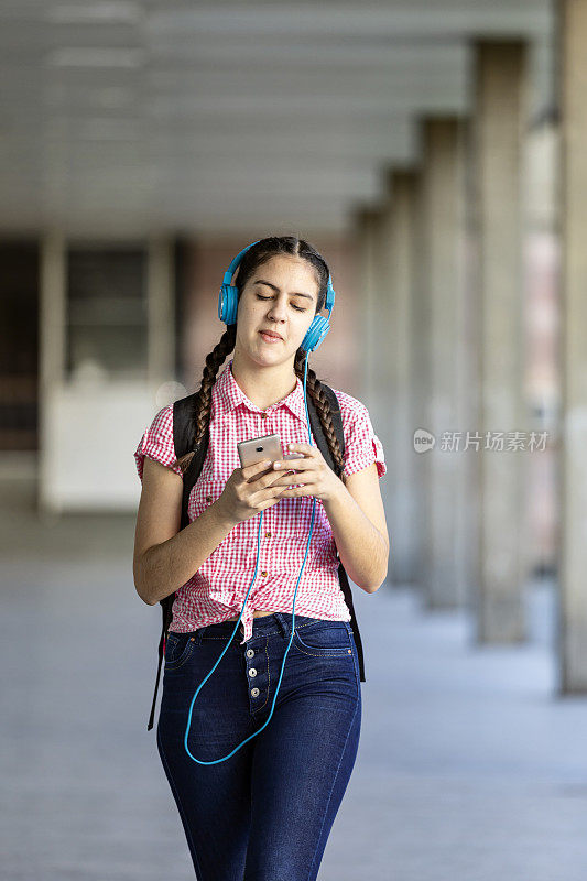 少女走在街上听着音乐