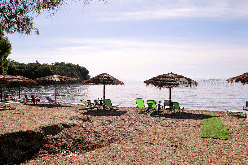 孤独的柳条太阳伞在海边海边。天然竹制遮阳伞、夏日遮阳伞、躺椅、桌椅、太阳床、躺椅、沙滩日光浴阳伞等供游客使用。