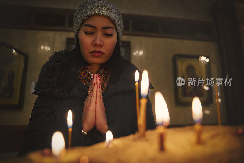 女人在教堂祈祷，蜡烛在大教堂，希望的概念