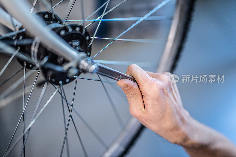 修理工在车间里拧紧一个自行车轮子。