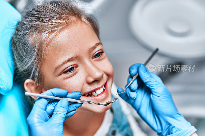 到牙科诊所进行牙齿检查。牙医在牙医的椅子上检查女孩的牙齿