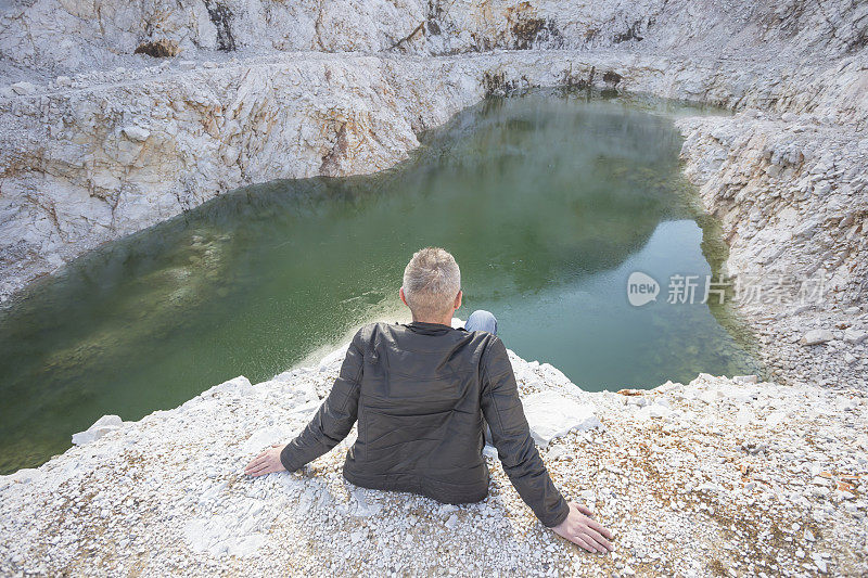 成年游客坐在悬崖边，在一些废弃的大理石采石场