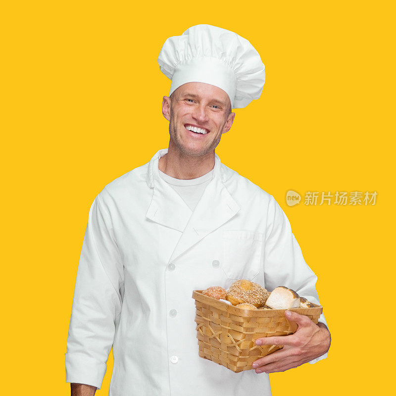 白种人年轻男性面包师前面黄色背景穿着裤子，拿着法棍