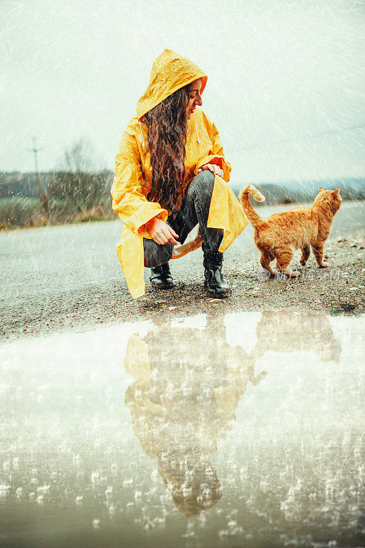 快乐的女孩和猫在大自然的雨