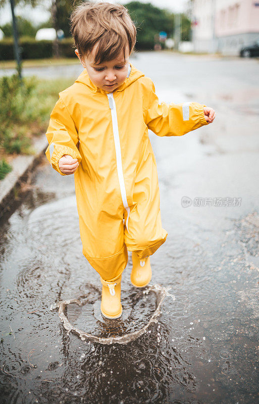 小男孩在雨中玩耍，跳进水里画画