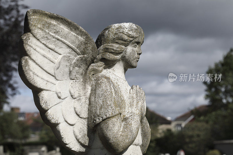 墓园天使雕像在阳光下暴雨后乌云密布