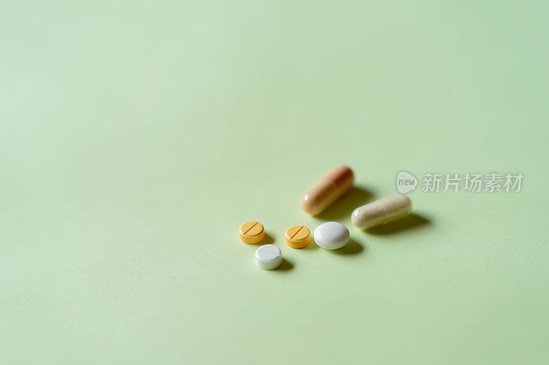 多种药物，包括药丸和胶囊，在柔和的绿色纸。