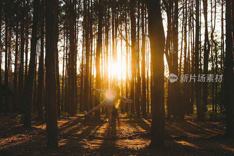 年轻女子在美丽的森林里奔跑，夕阳西下