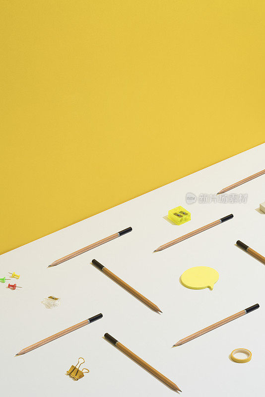 文具、办公用品平铺在黄白相间的背景上。