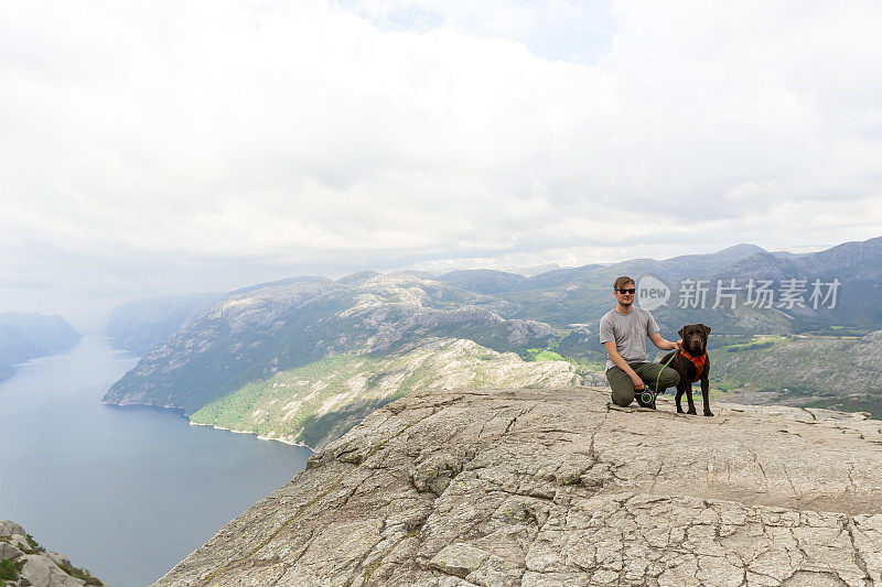 一只公犬和他的拉布拉多寻回犬在长途跋涉后欣赏布道石的风景