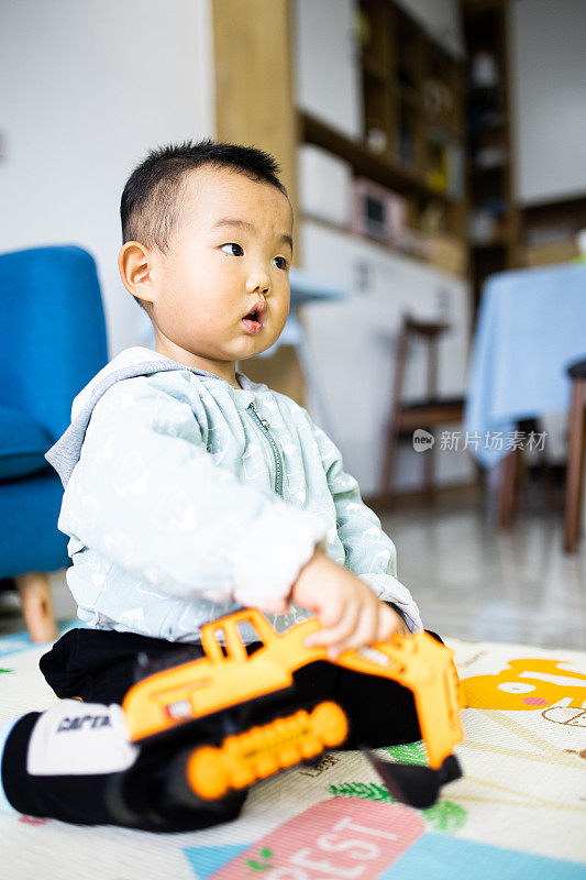 小男孩坐在地板上玩玩具车