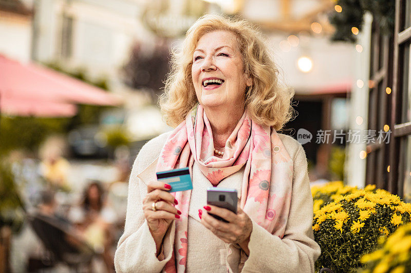 快乐的老女人在街上网上购物