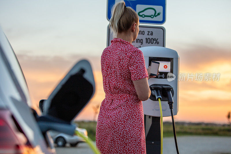 一名女子在充电站为电动汽车充电