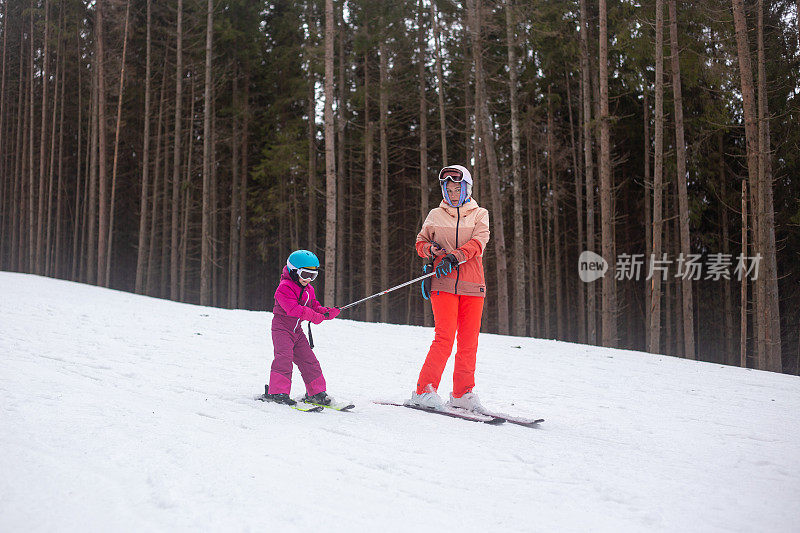 那孩子正和他母亲一起滑雪。