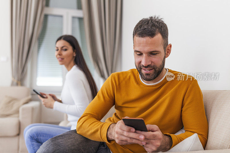 妻子背对丈夫，看情人的手机短信，男人在手机上玩游戏。欺骗和不忠的概念