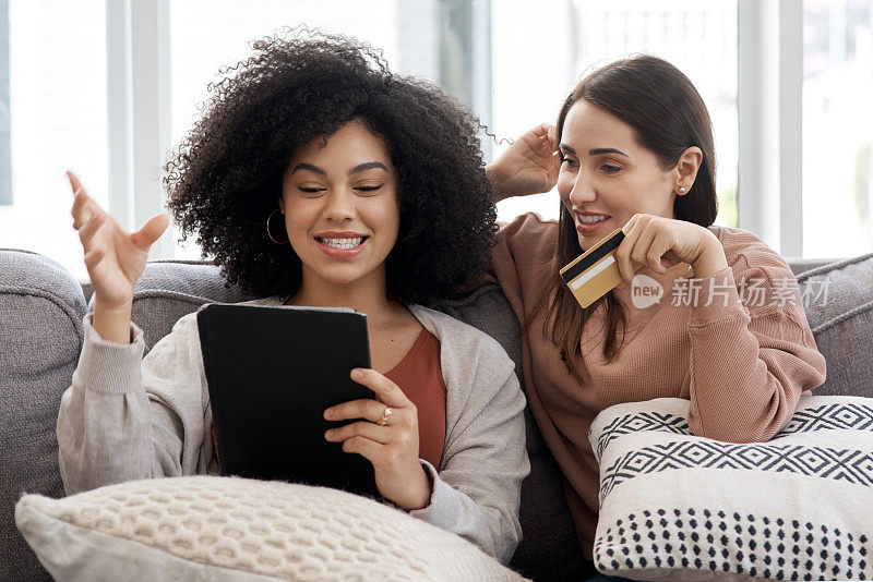 两个年轻女人坐在家里的沙发上在网上购物