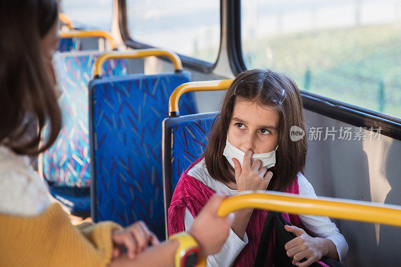 年轻女孩坐在公共汽车上调整防护口罩