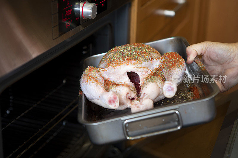用手将整只生鸡放入不锈钢烤盘，然后放入家用烤箱