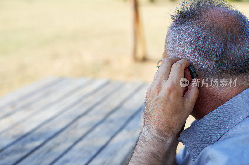 一个老人在户外戴着助听器