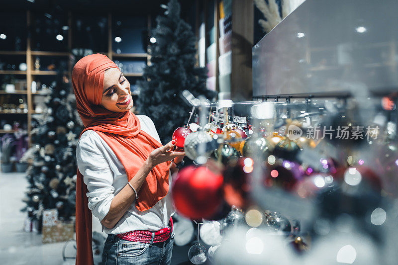 迷人的穆斯林中年女士手持装饰圣诞树。